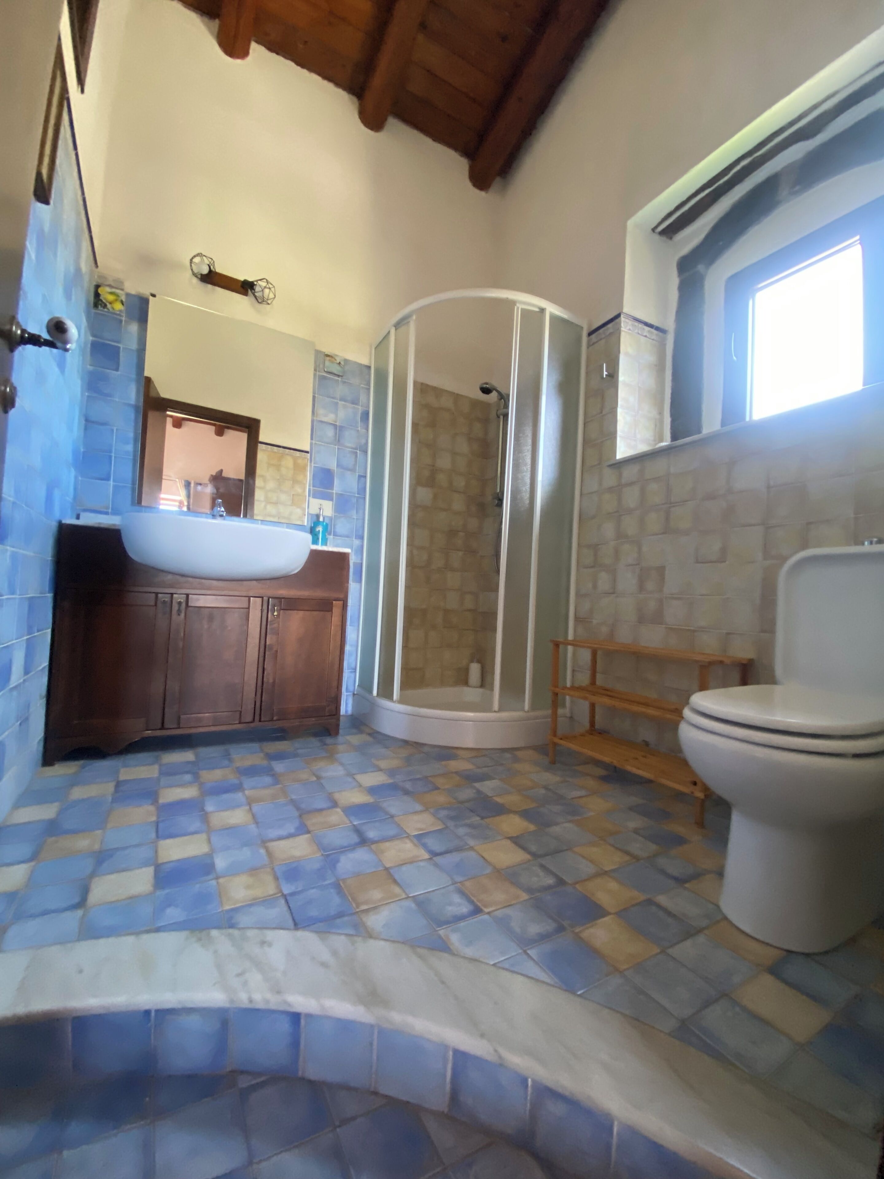 A bathroom with a sink, toilet, shower, and tiled floor.