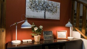 Un comptoir d’accueil agrémenté d’une pancarte de bienvenue encadrée, d’une plante en pot et de deux lampes de bureau.