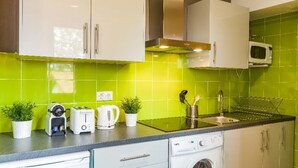 Une cuisine moderne avec des meubles blancs, un four à micro-ondes, un grille-pain et un lave-linge.