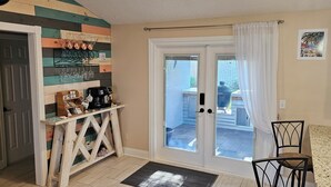 A room with a wooden wall, a coffee machine, a glass display, and a door leading to a balcony.
