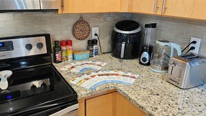 A kitchen with a Whirlpool stove, a coffee maker, a toaster, and various condiments on the counter.