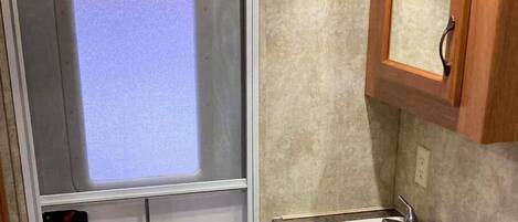 Une petite salle de bain comprenant un espace douche, un lavabo et des toilettes.