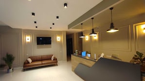 A hotel lobby with a reception desk, a brown leather sofa, and a flat-screen TV mounted on the wall. - The Brothers Suite (Dalaman)