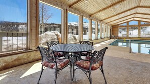 A covered outdoor area with a pool, wooden ceiling, and large windows offering a view of a snowy mountain landscape. - Mountain Retreat Close the Slopes (Brian Head)