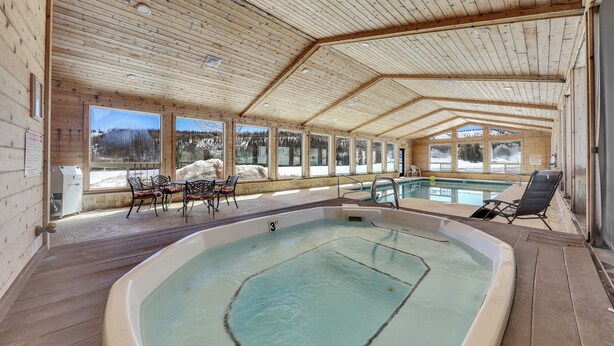 An indoor swimming pool with a view of snowy mountains through large windows. - Mountain Retreat Close the Slopes (Brian Head)