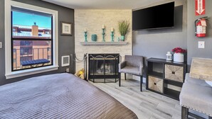 A modern bedroom with a large window, a fireplace, a TV mounted on the wall, and a bed with a headboard. - Mountain Retreat Close the Slopes (Brian Head)