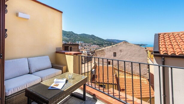 Ein Balkon mit einer Couch, einem Tisch und Blick auf Stadt und Berge.