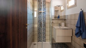 Ein Badezimmer mit Dusche, Waschbecken und Spiegel.