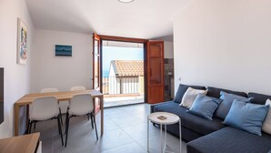 Ein modernes Wohnzimmer mit einer Couch, einem Esstisch mit Stühlen und einem kleinen runden Tisch.