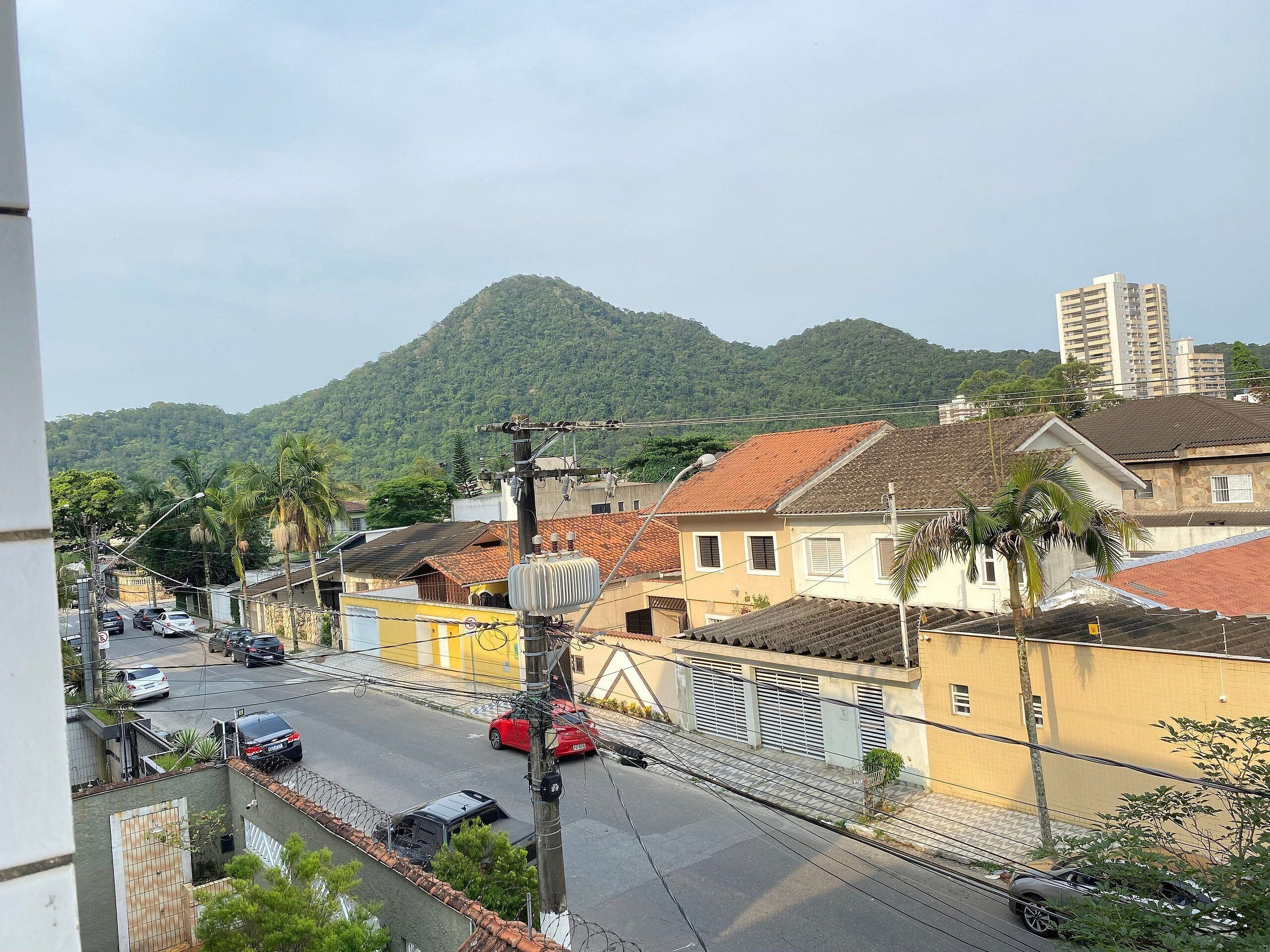 Une rue résidentielle bordée de maisons, avec une montagne en arrière-plan et un immeuble imposant.