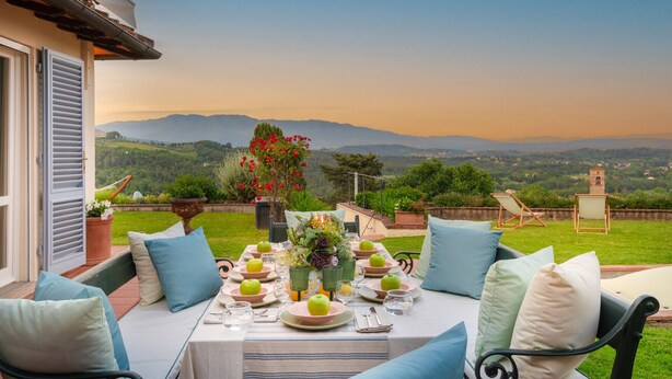 A dining table set outdoors with a view of mountains. - Fairytale Farmhouse Villa with Views and Pool (Lucca)