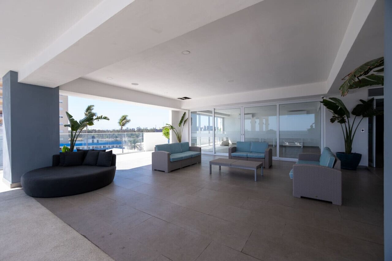 A spacious outdoor lounge area with modern seating and large windows offering views of the city.