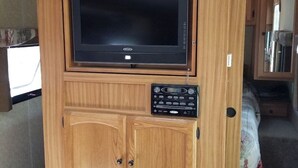 A compact kitchen with a built-in TV, wooden cabinetry, and a granite countertop. - The Riverside Dutchmen.  Reconnect with nature (Petit Étang)