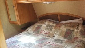 A bedroom with a wooden headboard, a quilted bedspread, and wooden cabinets above the bed. - The Riverside Dutchmen.  Reconnect with nature (Petit Étang)