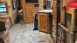 A compact kitchen with wooden cabinets, a built-in stove, a sink, and a television. - The Riverside Dutchmen.  Reconnect with nature (Petit Étang)