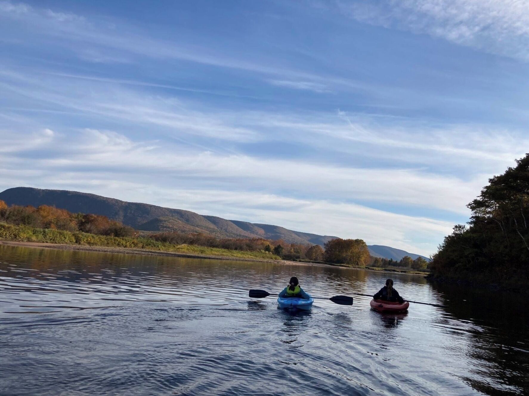 Deux kayaks sur une rivière paisible, avec des montagnes en arrière-plan.