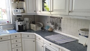 Una cocina moderna con armarios blancos, horno empotrado y cafetera.