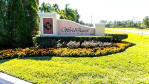 A sign for WorldQuest Resort with a landscaped garden in front.
