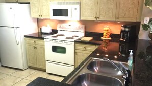 A kitchen with a stove, oven, microwave, sink, and cabinets.