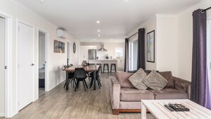 A modern apartment with a dining area, kitchen, and living room. - Cooks Family Retreat - Cooks Beach Holiday Home (Whitianga)
