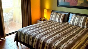 A hotel room with a bed, a ceiling fan, a nightstand, a lamp, and a view of the outside. - Marina Sol Resort Condo in Cabo
(Cabo San Lucas)