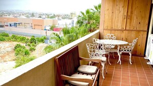 A balcony with a wooden bench, a small table, and white wicker chairs. - Marina Sol Resort Condo in Cabo
(Cabo San Lucas)