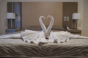 Habitación de hotel con una cama y una presentación de toallas con forma de corazón.
