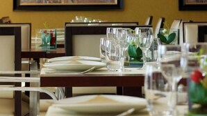 A dining area with tables set for service, framed artwork on the walls, and a warm color scheme. - Appart One Montreuil - Croix de Chavaux (Montreuil)