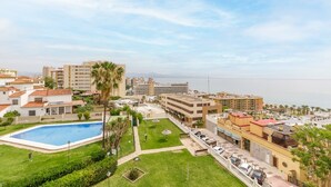 A resort with a swimming pool, a parking area, and a view of the sea.