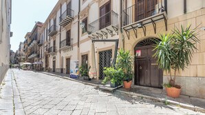 A cobblestone street lined with multi-story buildings, some with balconies and potted plants. - Olivella Apartment al Teatro Massimo by Wonderful Italy (Palermo)