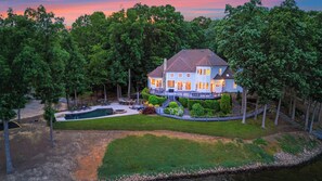 A two-story house with a swimming pool, deck, and a view of the surrounding forest. - Private Dock, Pool + Hottub, Game Room, Firepit Paradise Pointe by Avantstay (Sherrills Ford)