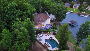 A large house with a swimming pool, surrounded by dense trees and a body of water. - Private Dock, Pool + Hottub, Game Room, Firepit Paradise Pointe by Avantstay (Sherrills Ford)