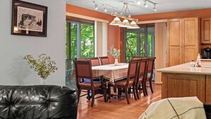 Ein Essbereich mit Holztisch und -stühlen, eine Küche mit Holzausstattung und ein gerahmtes Bild an der Wand.