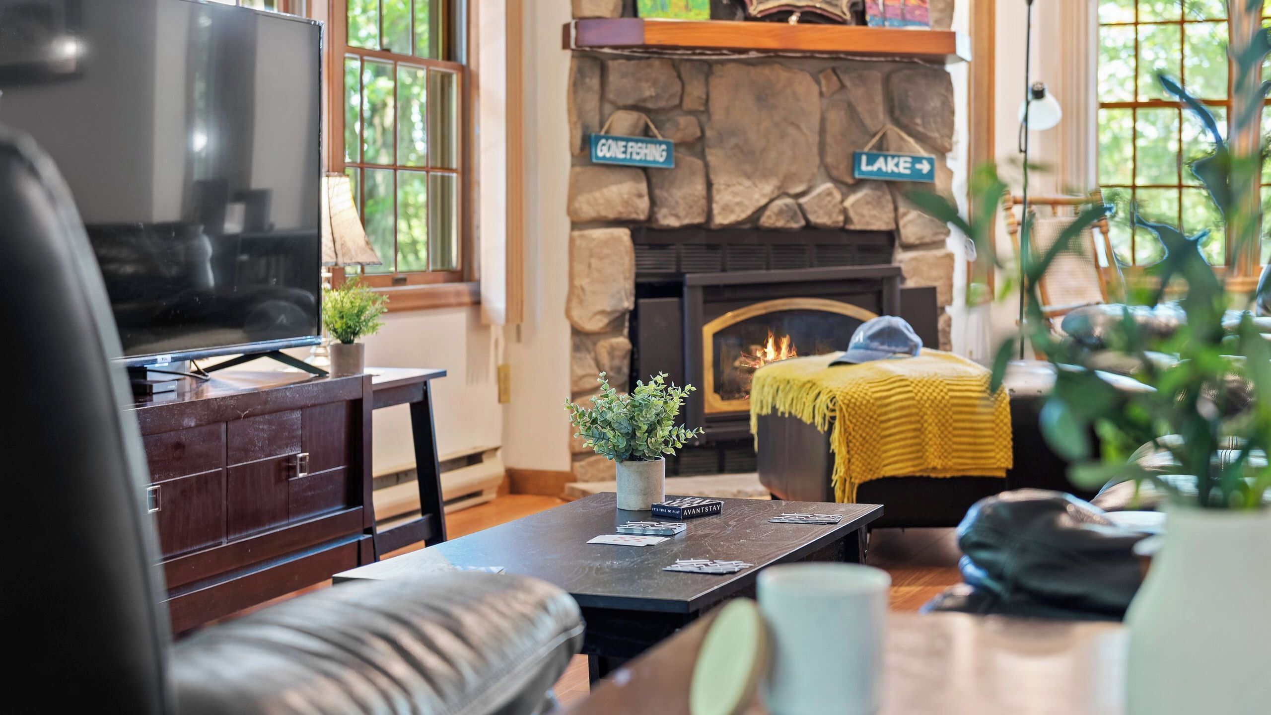 A cozy living room with a stone fireplace, a flat-screen TV, and a comfortable seating area.