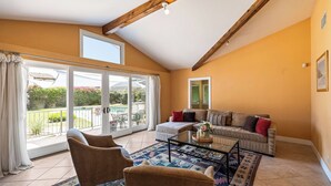 En rummelig opholdsstue med en stor skydedør til en balkon, en sofa og et sofabord.