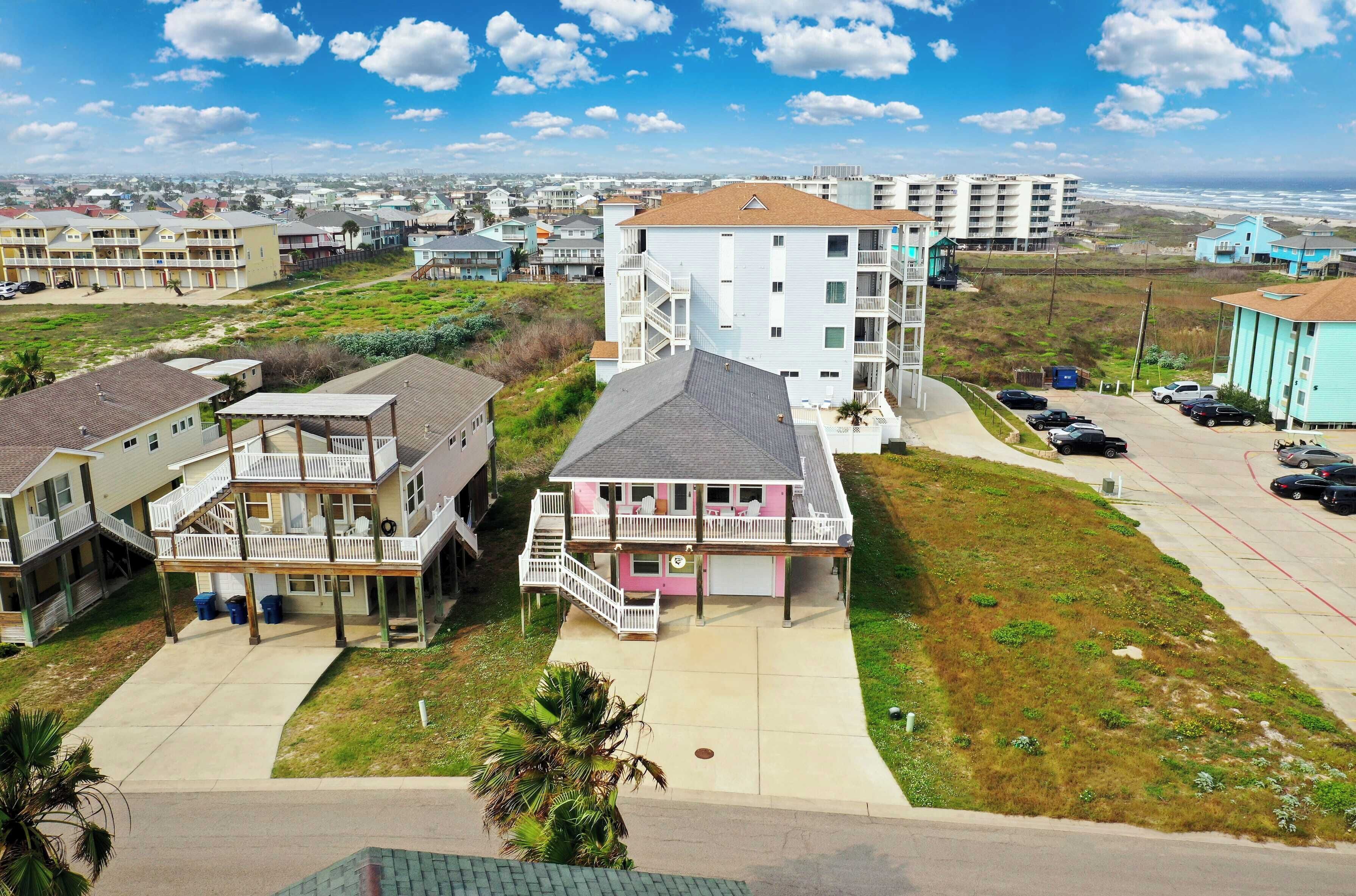 Un hotel de varios pisos con balcones, estacionamiento y vista al mar.