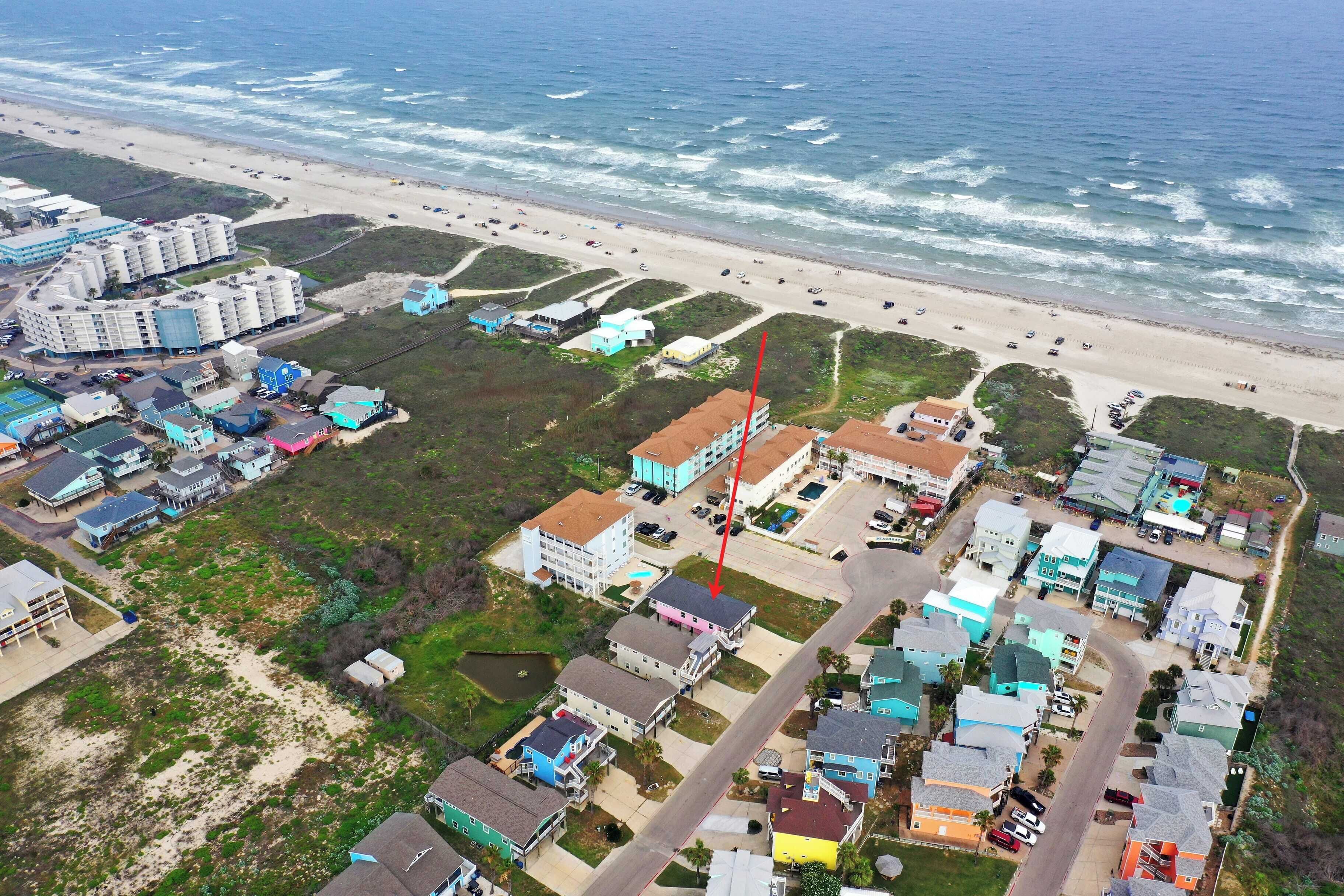 Vue aérienne d’une zone résidentielle côtière, avec des maisons, une plage et une route.