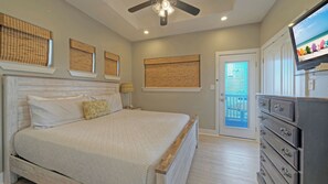 Un dormitorio con cama, cómoda, ventilador de techo y televisor.