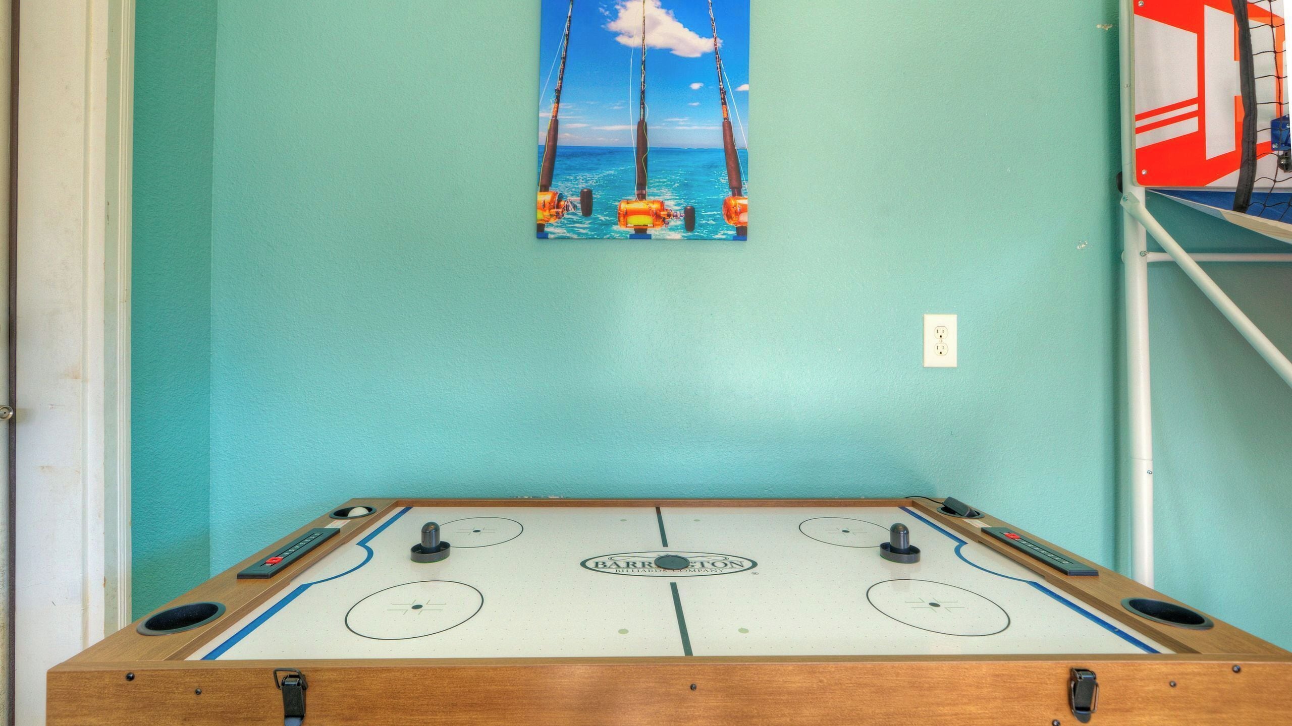 Una mesa de fútbol de mesa con vista al océano y un cuadro de una caña de pescar en la pared.