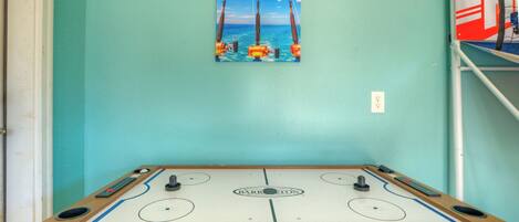 Una mesa de fútbol de mesa con vista al océano y un cuadro de una caña de pescar en la pared.