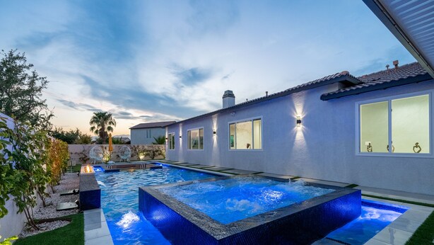 Una casa moderna con piscina, jacuzzi y un jardín bien cuidado.