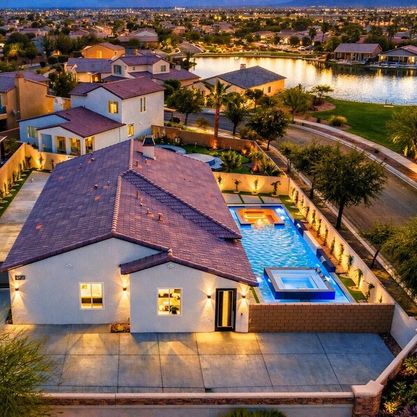 A residential area with a swimming pool, houses, and a lake in the background.