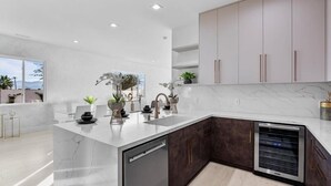 Une cuisine moderne dotée d’un plan de travail en marbre, de meubles de rangement aux couleurs sombres et d’un lave-vaisselle encastré.