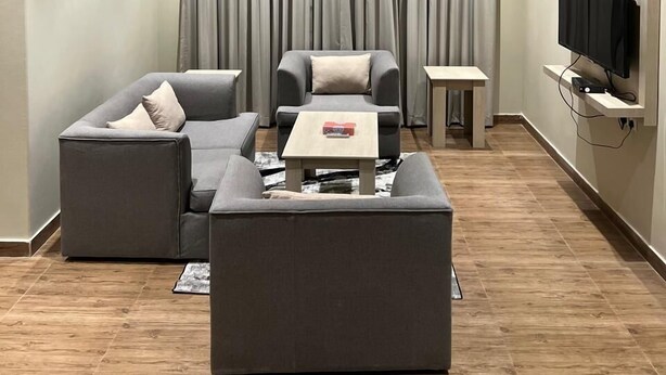 A modern living room with a sectional sofa, a coffee table, and a TV mounted on the wall.