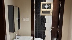A modern bathroom with a wooden floor, a white sink, and a toilet.