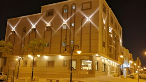 A multi-story building with a symmetrical facade, illuminated by street lamps and decorative lighting.