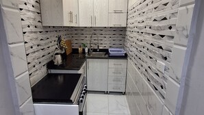 A compact kitchen with white marble tiles, a built-in oven, and a sink. - Egypt Hurghada Apartment  (Hurghada)
