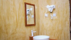 A bathroom with a wooden vanity, a round sink, a mirror, and two hair dryers mounted on the wall. - zanzigo (Nungwi)