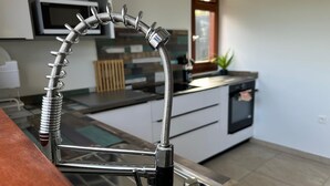 Ett kök med en modern kran i rostfritt stål, en mikrovågsugn och en diskmaskin.