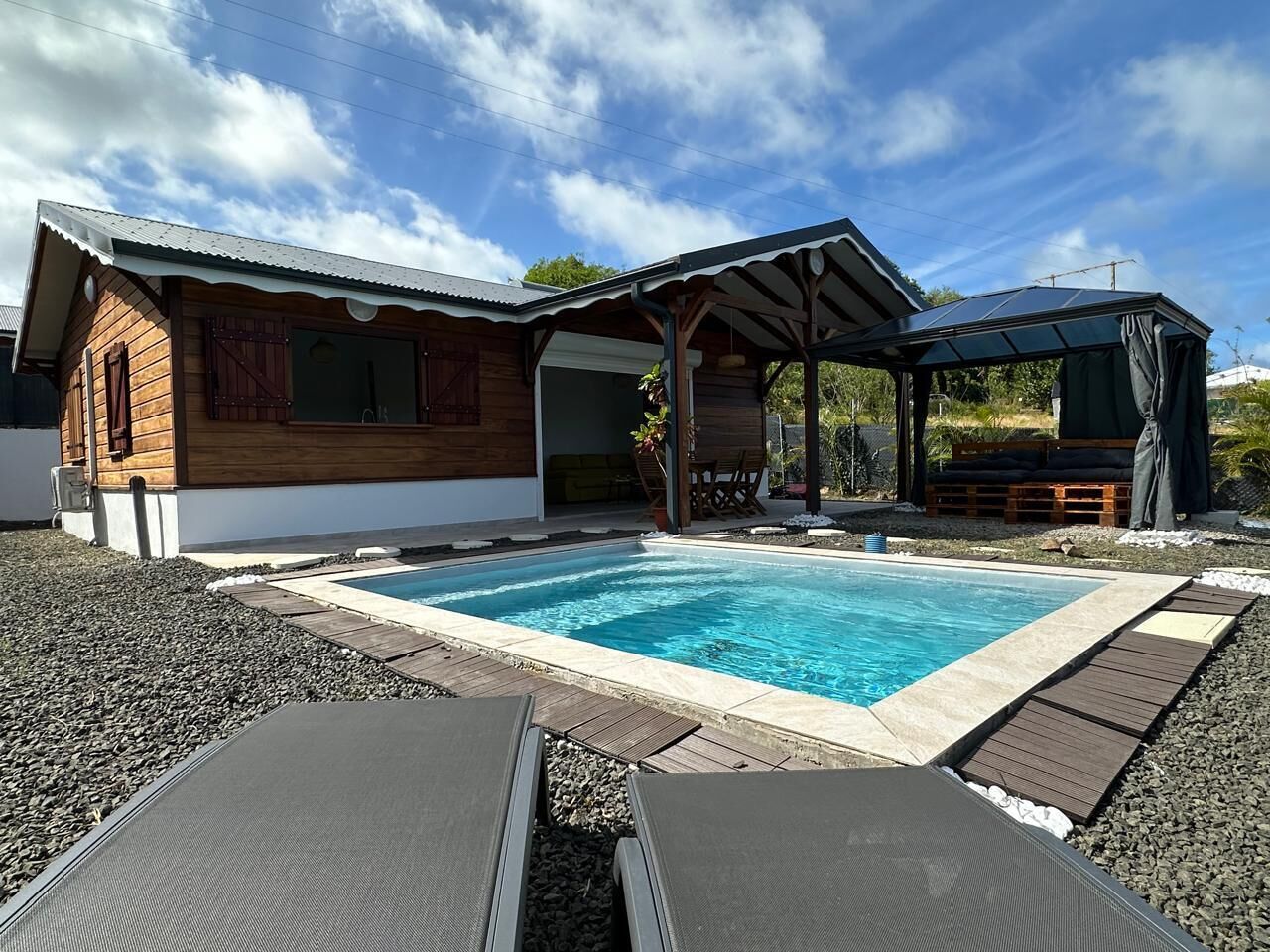 Una casa moderna con piscina, terraza de madera y zona de estar al aire libre.